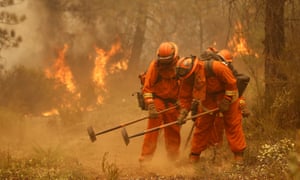 A California Department of Corrections and Rehabilitation inmate work crew builds a containment line ahead of flames from a fire near Sheep Ranch, California.