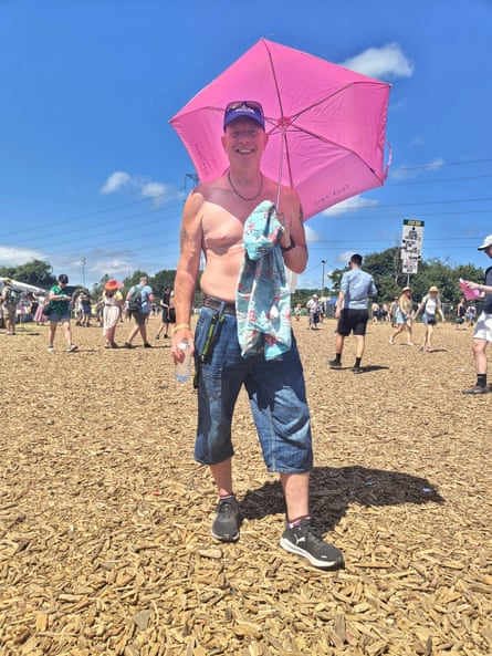 A shirtless man holding a pink umbrella