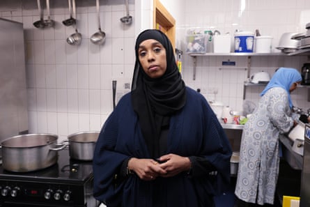 A woman in a headscarf standing in a kitchen looking at the camera