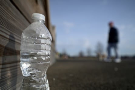 a bottle of water with a person walking by it