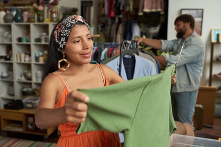 A woman looking at a t-shirt in a thrift shop