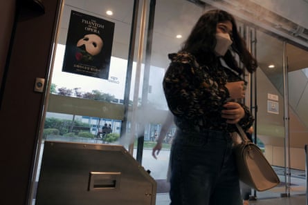 A woman is sprayed with disinfectant as she enters the Seoul theatre showing The Phantom of the Opera.