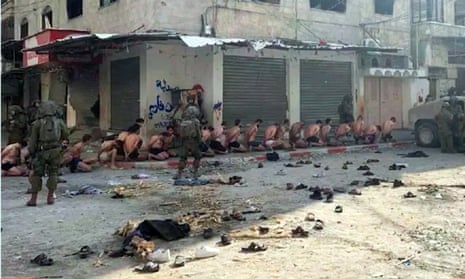 Prisioneros palestinos desnudos hasta quedar en ropa interior sentados contra la pared
