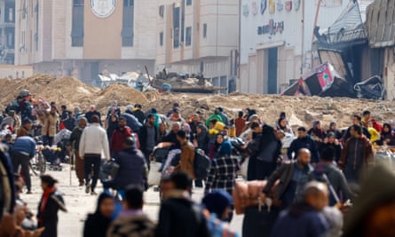 An Israeli tank stands amid the rubble as Palestinians fleeing Khan Younis move towards Rafah