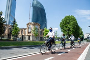 Four cyclists wearing protective masks ride along a new cycle path in Milan.