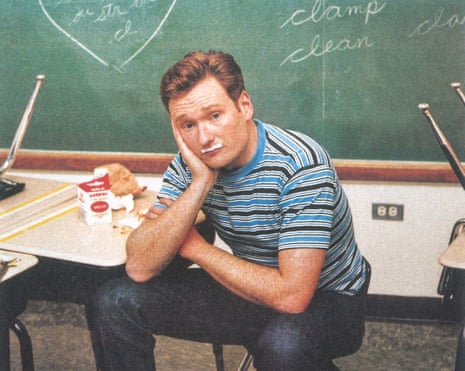 Conan in t-shirt and jeans in school classroom, with milk mustache