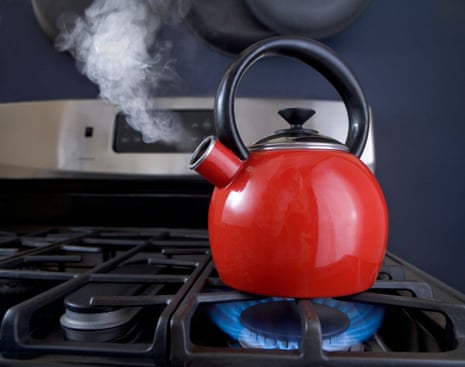 A red teapot is on the boil and steam is pouring out of the spout.