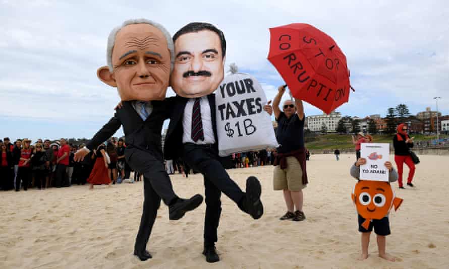 Protesters wearing masks depicting Malcolm Turnbull and Gautam Adani at Sydney’s Bondi beach