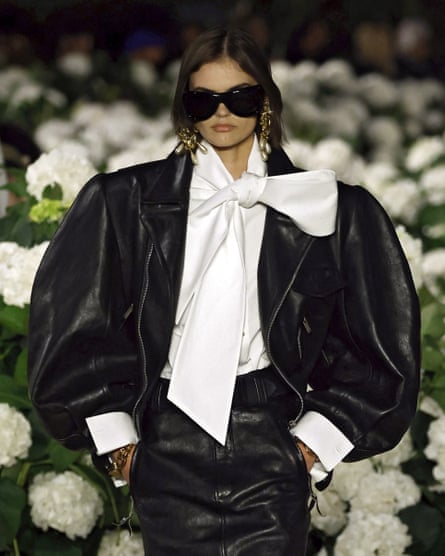 Model wearing white blouse with large pussy bow, beneath a black jacket with voluminous sleeves