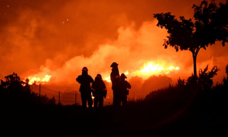 Los Angeles county firefighters keep watch on the Bobcat Fire as it burns through the night in Juniper Hills, California on 19 September.