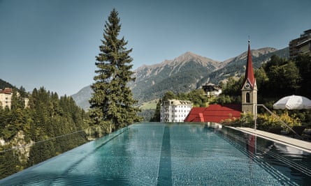 Swimming pool in front of a building, trees and high mountains