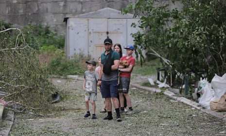 A family stands near a residential building damaged in recent shelling in the city of Bakhmut, Donetsk region, eastern Ukraine, 13 June.