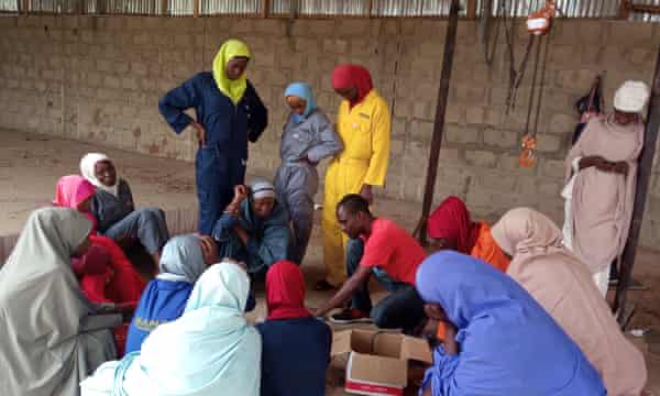 A man instructs a circle of young women in the workshop