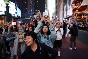 People take photographs of the sunset at 42nd Street in Times Square