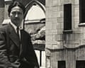 A black and white photo of a Japense man in the 1940s called Kiyoshi Tanimoto in front of damaged buildings.
