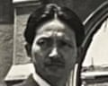 A black and white photograph by Kiyoshi Tanimoto in front of the ruined buildings.