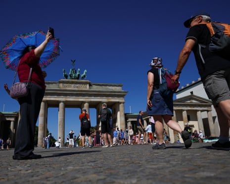 People shelter from the sun with umbrellas and hats as they visit the Brandenburg Gate on a hot summer day, as a heatwave hits Berlin, Germany.