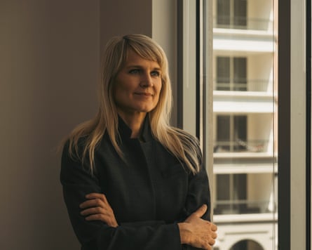 Renata Briggman in a black shirt next to a window with a balconied building outside