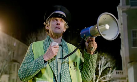 Peter Capaldi in Paddington 2, wearing a cap and a hi-vis jacket, and holding a megaphone