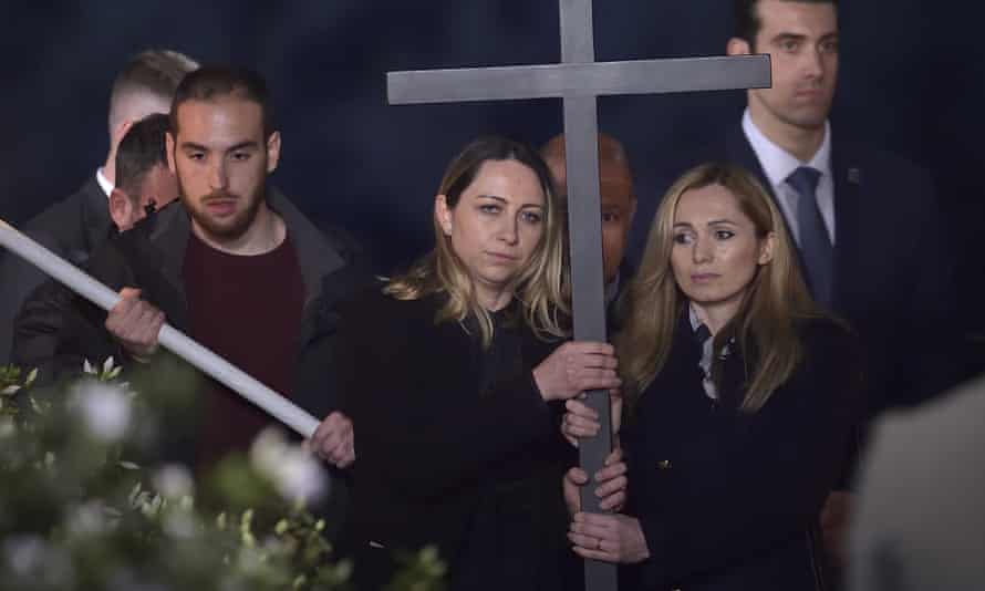 Two women, one from Ukraine and the other from Russia, hold the Holy Cross as Pope Francis attends the Way of The Cross at the Colosseum on Good Friday in Rome, Italy.