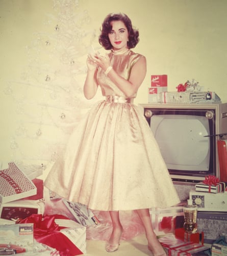 Elizabeth Taylor wearing a gold midi dress with full skirt, gold shoes and red lipstick