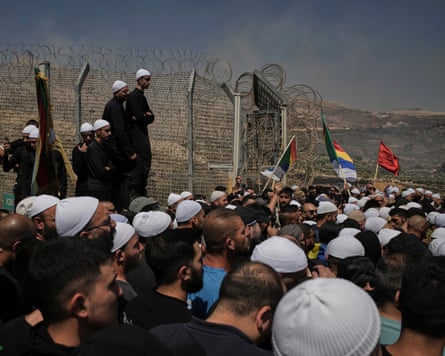 Members of the Israeli Druze community gather at the border fence separating the Israeli-controlled Golan Heights and Syria