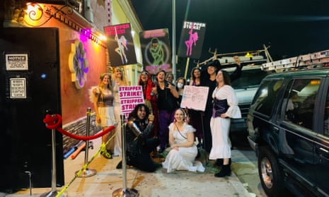 A group of people hold signs reading 'Stripper strike' outside of a club.