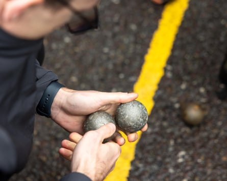 A close-up of a man looking at two iron balls he is holding in his hands