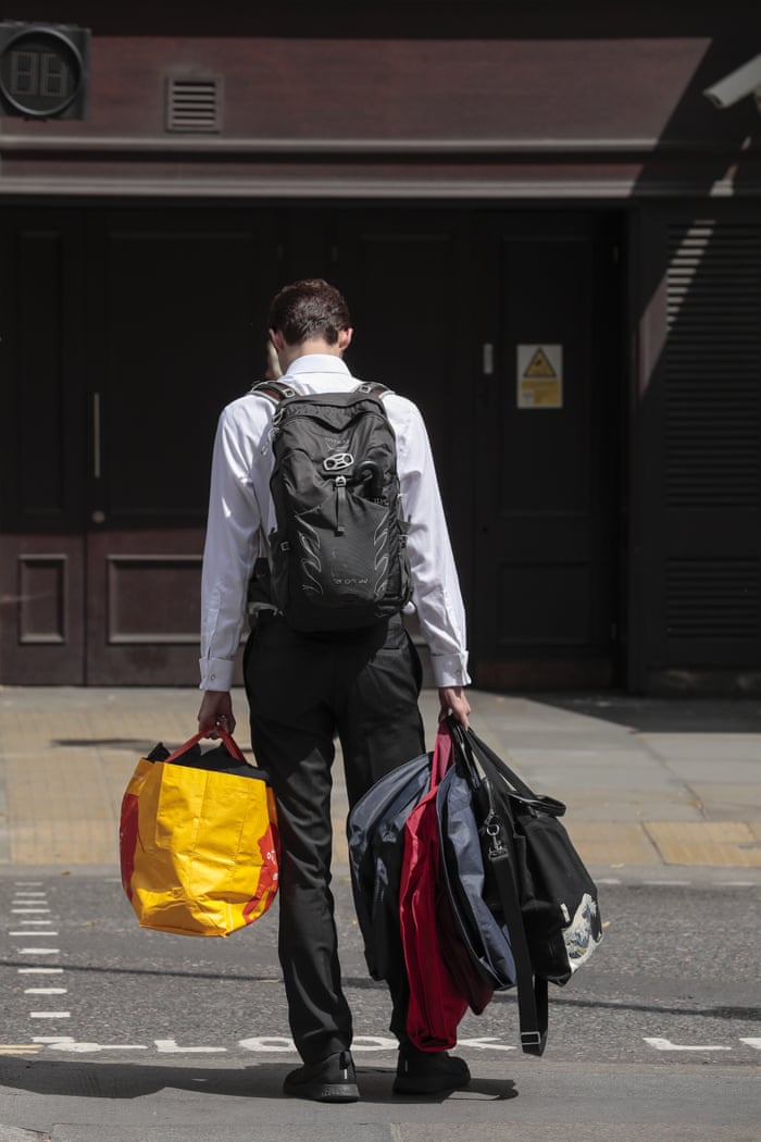 A man holds bags and suit carriers as he leaves the offices of Deutsche Bank in London today.