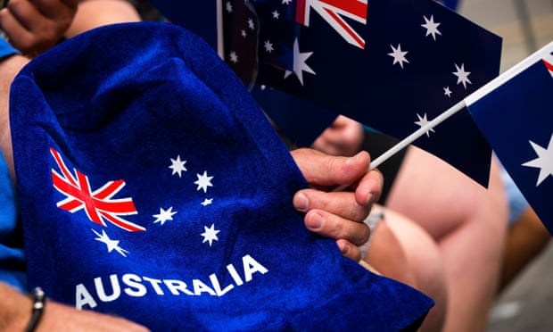 People wave flags and festive merchandise to celebrate Australia Day in Melbourne in 2017.