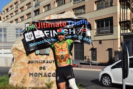 A man holds a banner in Monaco, celebrating the end of a triathlon.