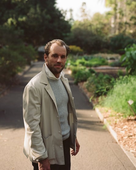 A stylish man in a beige jacket and grey knit jumper