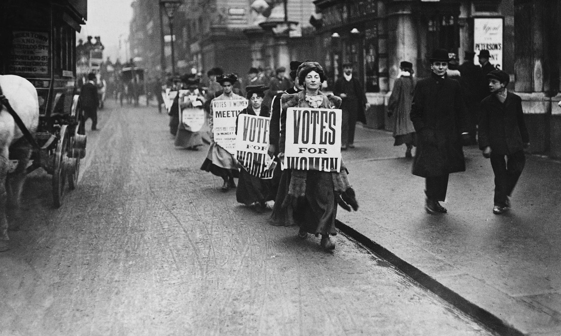 Suffragettes walk along a London street wearing sandwich boards demanding that women be given the vote. 1912.