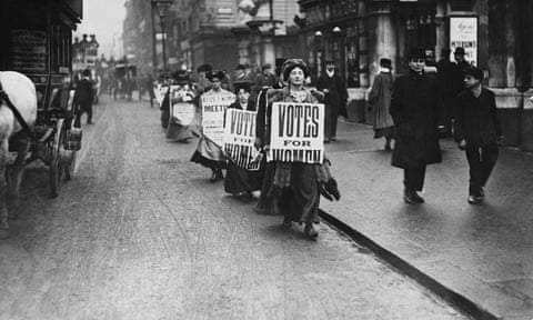 Suffragettes walk along a London street wearing sandwich boards demanding that women be given the vote. 1912.