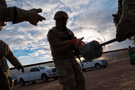 three people wearing soldier uniforms unwind wire outside