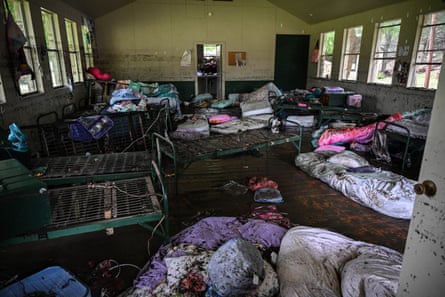 A view inside a cabin after the flood swept through showing mattresses, beds, bedding and baggage strewn around and covered in mud.