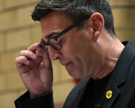 Andy Burnham adjusting his glasses.