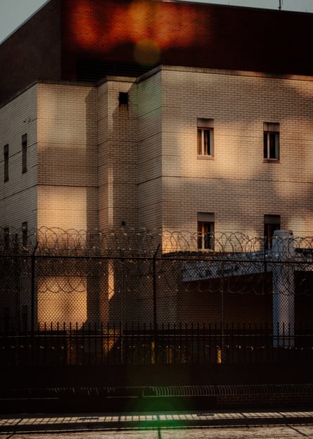 A large beige building with small windows and a high-security fence around it