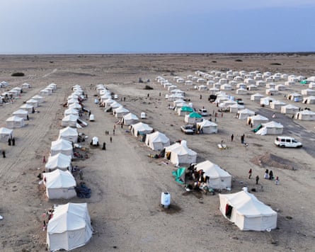 Row after row of white canvas tents set up in a desert-like terrain