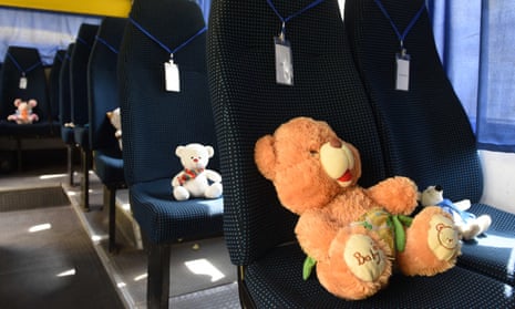 Stuffed toys symbolising each of 243 killed Ukrainian children sit on seats in an empty yellow school bus.