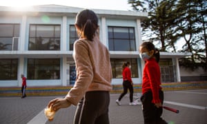 Girls wearing masks play badminton at Taoranting Park on March 21, 2020 in Beijing, China.