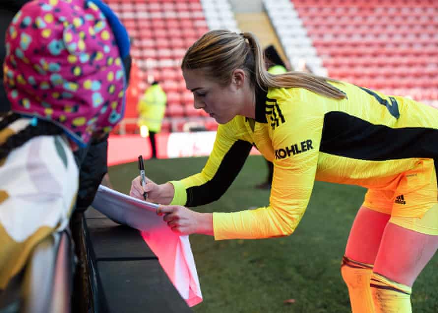 Manchester United goalkeeper Mary Earps signs a young fan's England shirt.