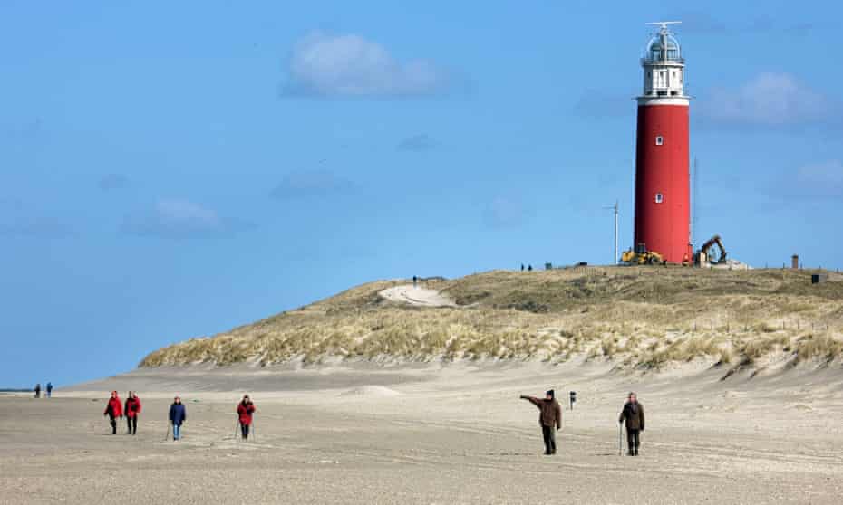 Walkers on the beach and lighthouse at Cocksdorp