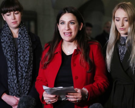 Luciana Berger stands with two women either side of her reading from notes in her hand