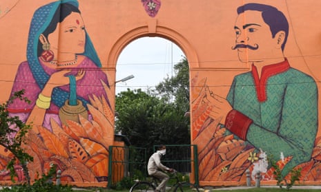 A man on a bicycle rides past a mural depicting a bride and a groom during a marriage ceremony, in Delhi on 31 August 2020. 