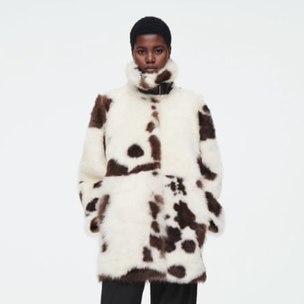 A model wears a white and brown funnel-neck shearling coat