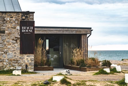 Entrance to modern-looking restaurant with sea in the background.