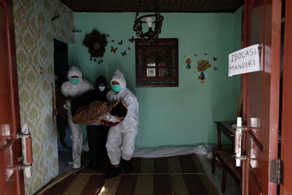 Relatives wearing personal protective equipment carry the body of 64-year-old Yoyoh Sa’diah, who died from Covid whilst isolating at her home, to be embalmed in Bogor, West Java province, Indonesia.