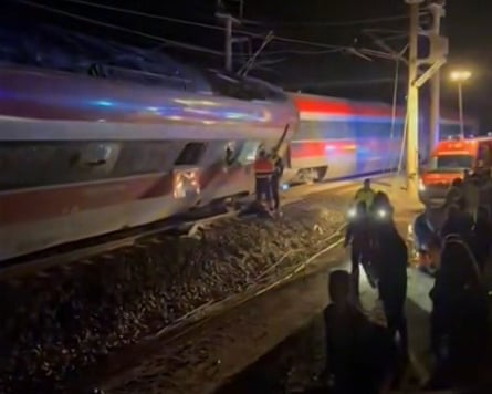 Rescue workers with head torches beside two connected train carriages, one leaning at an angle