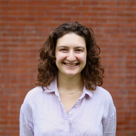 a woman smiling in front of a brick wall